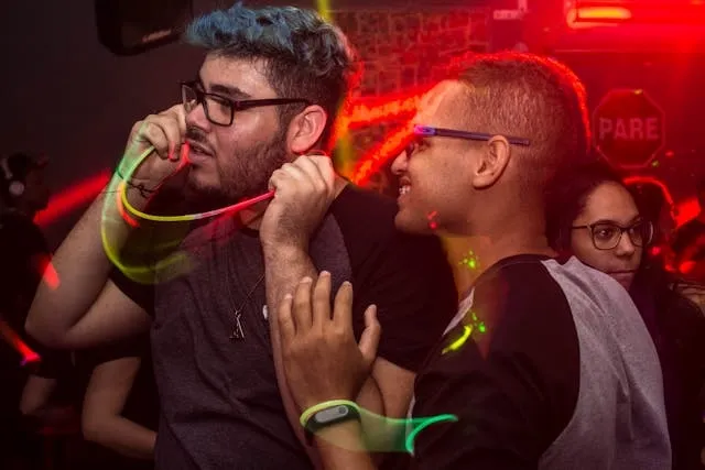 two men holding glow sticks under a bright red light for neon theme party