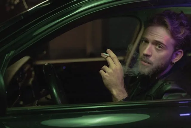 a man smoking a cigarette inside a car for best car air freshener for smokers