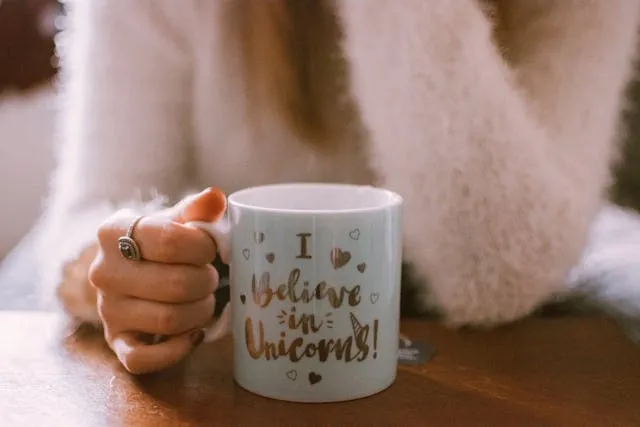 a woman holding a mug that says i believe in unicorns for how to make custom mugs