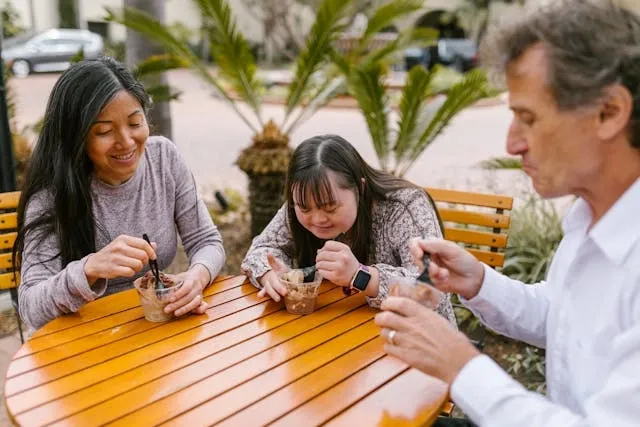 three people enjoying desserts around an outdoor wooden table for diy outdoor table ideas