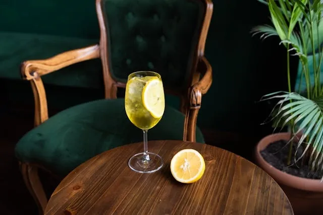 a cocktail drink and a slice of lemon on a table for cocktail table set up