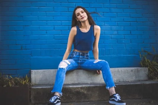 a woman wearing blue jeans against a blue wall for how to patch jeans crotch