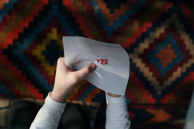 a person embroidering the word yes in red for how to embroider letters