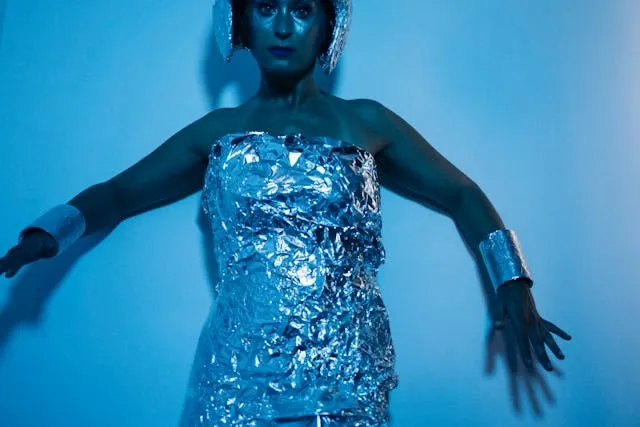 a woman wearing a tin foil dress illuminated with blue light for electric blue neon blue aesthetic