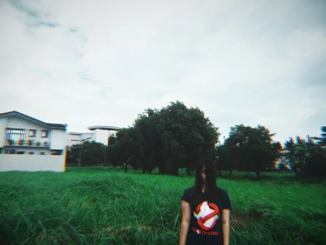 a person standing in long grass wearing a black ghostbusters t-shirt for ghostbusters patch placement a person standing in long grass wearing a black ghostbusters t-shirt for ghostbusters patch placement