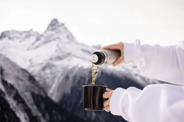 pouring a drink into a mug in front of mountains for best travel coffee mug pouring a drink into a mug in front of mountains for best travel coffee mug