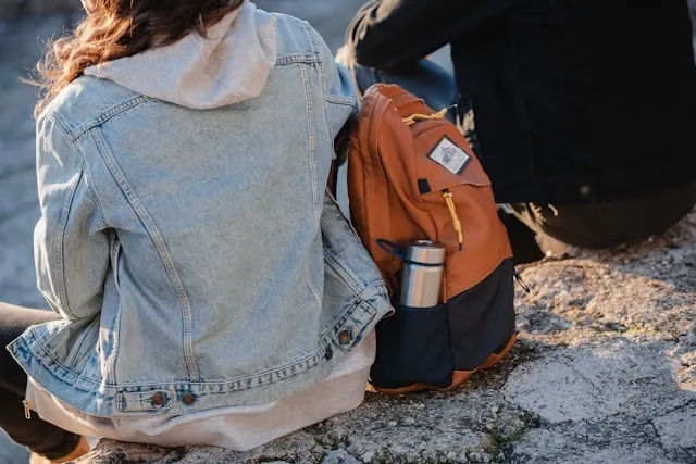 a person sitting beside a backpack for how to put a patch on a backpack a person sitting beside a backpack for how to put a patch on a backpack