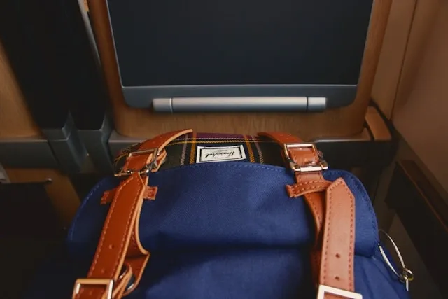 a blue backpack in front of a seat for is a backpack a personal item a blue backpack in front of a seat for is a backpack a personal item