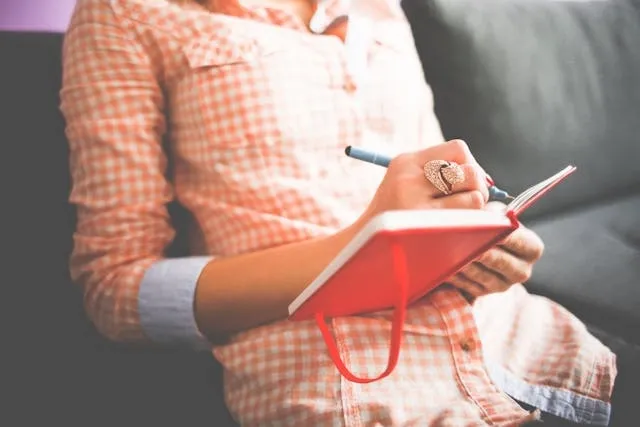 a person writing in a red notebook for how to journal for mental health a person writing in a red notebook for how to journal for mental health