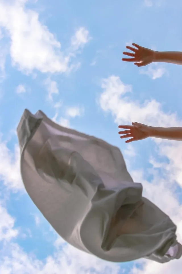Tablecloth being thrown into the air with sky background for how to wash polyester tablecloths