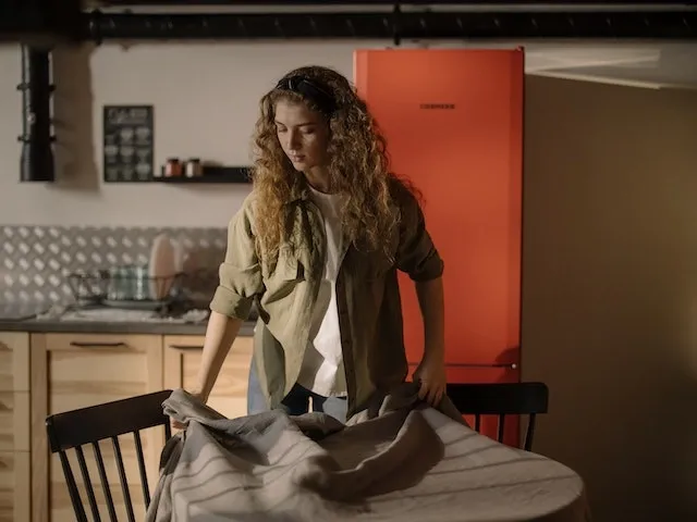 Photo of a woman removing a tablecloth from a table for How Should You Store Tablecloths